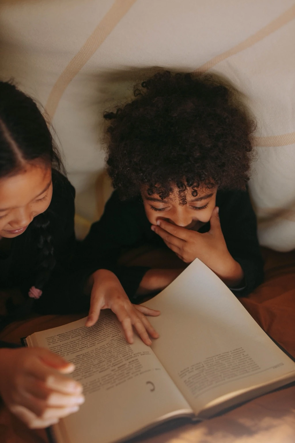 Twee kinderen lezen samen in warm licht als beeld voor basisschoolbegeleiding.