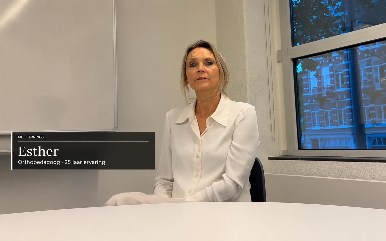 Esther, orthopedagoog met 25 jaar ervaring, zittend in een rustige werkruimte.
